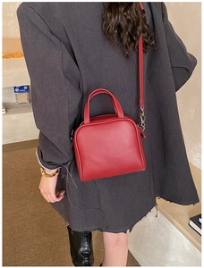 Chic red square handbag with top handle and shoulder strap shown in lifestyle setting