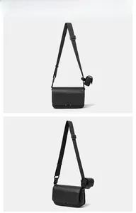 Detail of black crossbody bag with textured leather, wide strap and mini earphone pouch