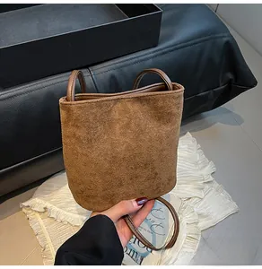 Détail d'un sac seau en cuir givré marron foncé avec anse fine et texture rétro