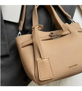 Détail du sac seau marron clair en cuir texturé litchi avec décoration de fermoir