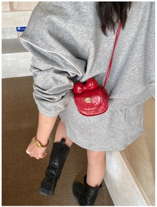 Vue arrière d'un mini sac bandoulière rouge avec nœud et détail d'ours en métal