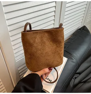 Détail du sac seau en daim marron avec poignées anneaux en cuir marron foncé