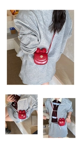 Mini sac bandoulière rouge avec gros nœud et fermoir ours doré porté par un modèle