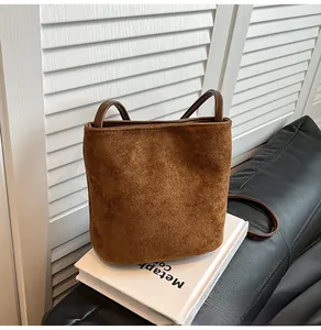 Gros plan sur la texture d'un sac seau en daim marron posé sur un livre blanc épuré