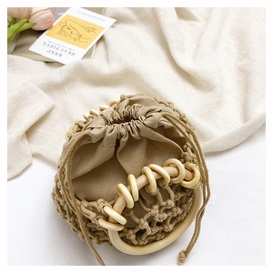 Detail of bohemian woven handbag with rounded wooden handles and drawstring inner pouch
