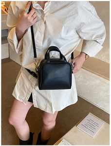 Modern black leather square bag worn cross-body style showing size and capacity on a model