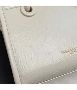 Detail view of cream handbag showing wrinkled leather texture and gold lettering