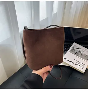 Détail d'un sac à main en daim marron foncé mat dans un décor d'intérieur chic