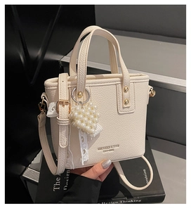 Close-up of off-white lychee pattern handbag with pearl heart charm and lace detail