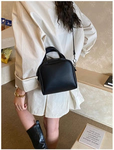 Detail view of the black square crossbody bag with silver hardware on a model