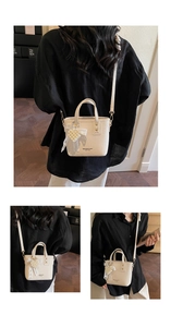 Detail of cream bucket bag with lychee texture, gold logo, and pearl heart charm