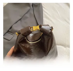 Close-up of dark brown oil wax leather handbag with golden buckle and pleated texture