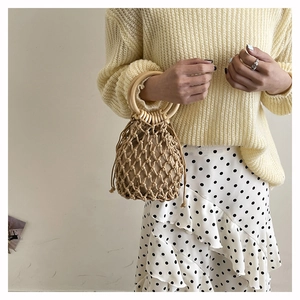 Detail of woven handheld bag featuring hollow mesh pattern and round wooden handles