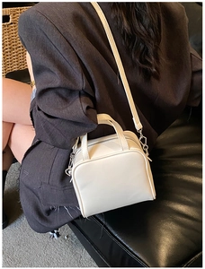 Detailed view of white minimalist square bag worn crossbody on a grey blazer outfit