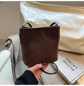 Détail d'un sac seau en daim marron foncé avec bandoulière fine au design élégant