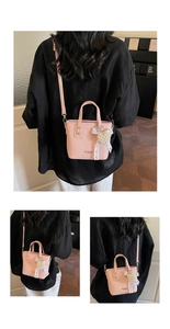Detail of pink lychee leather bag with pearl lace charm and brand logo imprint