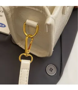 Detail of white crocodile pattern leather bag with polished gold metal hardware hook