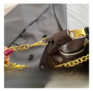 Detail of dark brown patent leather bag with bold gold chain strap and metallic clasp