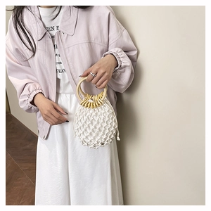 Close-up of white woven mesh bucket bag with large wooden handles and yellow bead accents