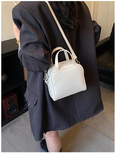 Rear view of a white minimalist square crossbody bag styled with a gray formal blazer