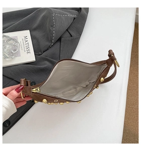 Détail intérieur du sac marron avec rivets, doublure grise, poche interne et fermeture