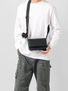 Minimalist black pebbled leather crossbody bag with small cylindrical strap pouch