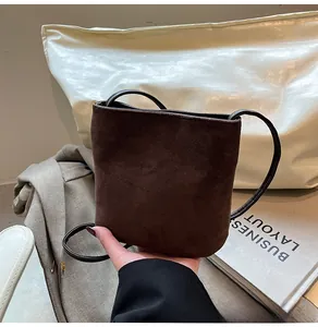 Détail d'un mini sac bandoulière en daim marron foncé avec fine bandoulière noire
