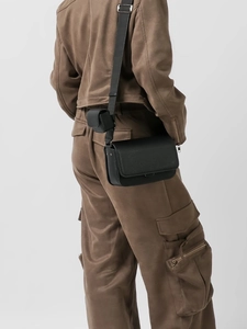 Minimalist black leather messenger bag with adjustable strap and small round coin pouch