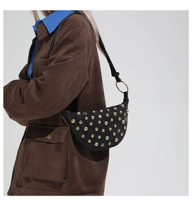 Détail du sac à bandoulière noir avec rivets dorés et texture en cuir vintage chic
