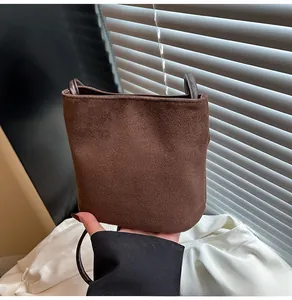 Gros plan détaillé sur la texture en daim marron mat et les coutures du sac seau minimaliste