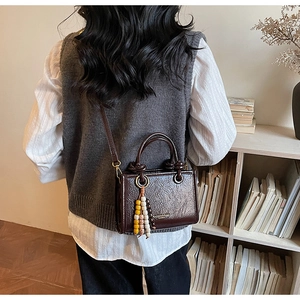 Detail of dark brown wax leather crossbody bag with colorful wooden bead tassel accessory
