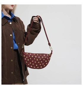 Détail du sac demi-lune bordeaux avec clous dorés et accents de style punk chic