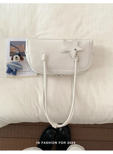 Close-up of minimalist white leather rectangular shoulder bag with star charm and long straps