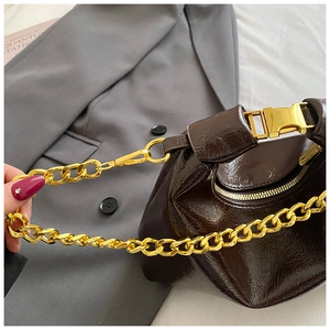 Close-up of deep brown patent leather bag with gold chain strap and crinkle texture