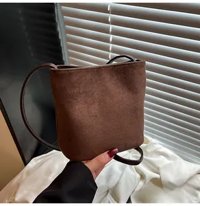Détail d'un sac seau en daim marron givré avec une fine bandoulière en cuir