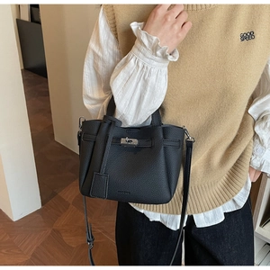 Détail du sac seau en cuir grainé noir avec fermoir tournant en métal argenté et logo