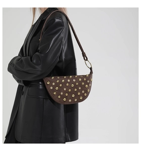 Détail d'un sac demi-lune marron foncé orné de rivets et d'oeillets dorés