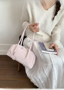 Close-up of pink leather Boston bag with star charm and zip closure held by a model