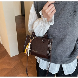 Detailed macro view of chocolate embossed leather handbag with chic beaded charm accessory