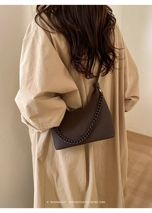 Dunkelbraune Halbmond-Schultertasche mit Lychee-Struktur und Metallkette an einem Model