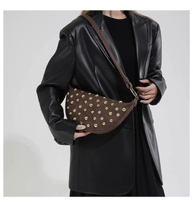 Détail du sac demi-lune en daim marron avec rivets dorés et œillets métalliques