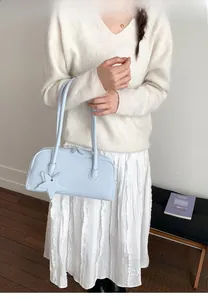 Detail of light blue faux leather tote with star charm and double zipper top closure