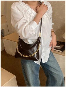 Deep brown crescent shoulder bag featuring a chunky gold chain and thin leather strap