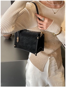 Detail of black matte leather handbag featuring contrast white stitching and gold hardware