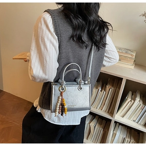 Silver metallic crossbody tote with wrinkled texture and bohemian bead charm detail
