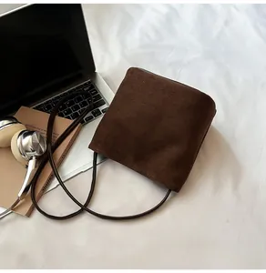 Vue détaillée de la texture en daim marron foncé sur un sac seau au design minimaliste