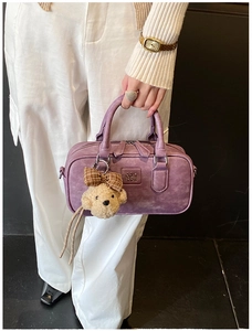 Détail du sac boston violet vintage avec breloque ours en peluche et logo embossé