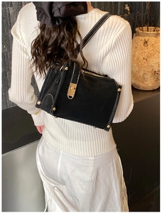 Detail of black box-shaped suede handbag with contrast stitching and golden turn-lock