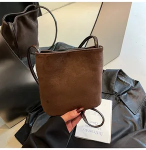 Détail d'un sac seau en cuir dépoli marron foncé avec une texture souple et des bords nets