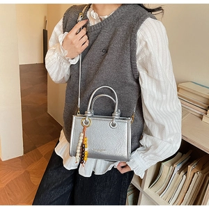 Detail of silver metallic bucket bag with minimalist round handles and beaded charm decor